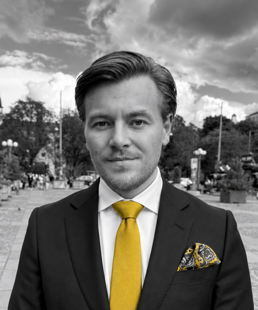 Timmy Edebjörk Säberg i svartvit kostymbild med gul slips och mönstrad näsduk.